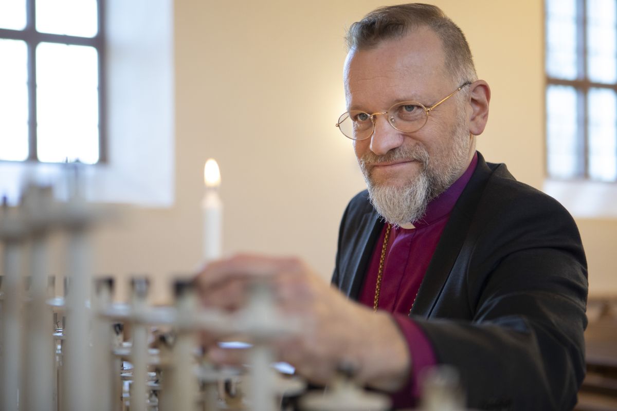Piispa Jari Jolkkonen sytyttää kynttilää Kuopion Tuomiokirkossa.