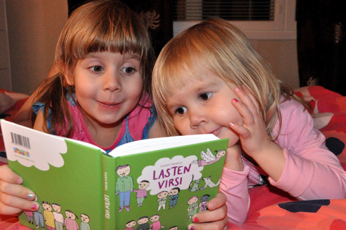 Kaksi lasta lukee kirjaa yhdessä. 